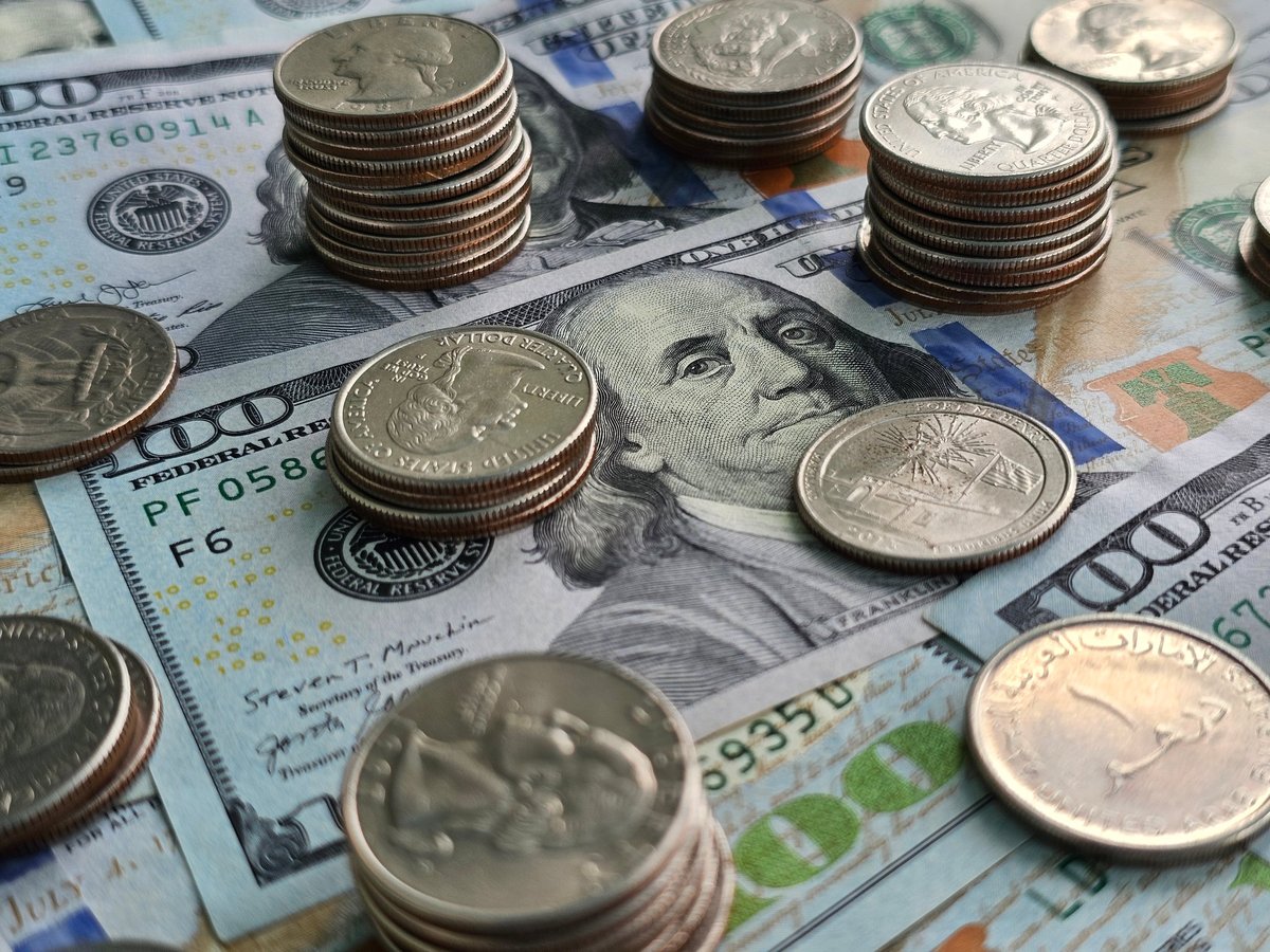 Stacks of coins and paper money spread across a table